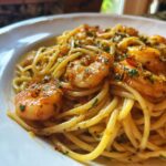 Close-up of Garlic Shrimp Pasta served on a white plate, garnished with herbs and a flavorful sauce.