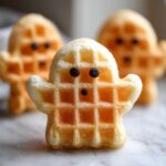 Three Ghost-Shaped Waffles for Halloween Morning, decorated with chocolate chips for eyes and mouth.