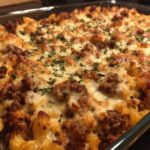 Close-up of a baked ground beef casserole with pasta, cheese, and parsley topping.