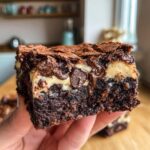 Close-up of a Homemade Baileys Fudge brownie slice, showing layers of chocolate, fudge, and a gooey texture.