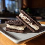 Two stacked Oreo Ice Cream Sandwiches on a gray plate, showing the creamy filling and cookie layers.