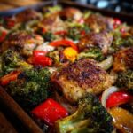 Close-up of a Simple Chicken Sheet Pan Dinner with chicken thighs, broccoli, peppers, and onions.
