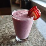 A glass of Strawberry Açaí Refresher garnished with sliced strawberries.