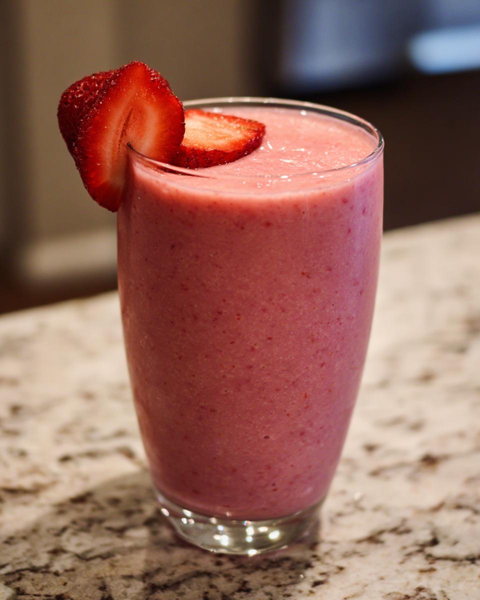 A glass of Strawberry Açaí Refresher garnished with fresh strawberry slices.