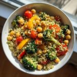 Overhead shot of a Vegetarian Meal Prep Bowls featuring quinoa, chickpeas, broccoli, tomatoes, and yellow bell peppers.