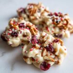 Close-up of White Chocolate Christmas Clusters with pretzels, cranberries, pecans, and festive sprinkles.
