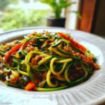 A plate of vibrant Zucchini Noodle Stir Fry with zucchini noodles, red bell peppers, and other stir-fried vegetables.