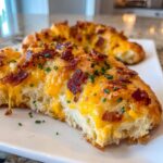 Close-up of a piece of bacon cheddar pull-apart bread, a 5-ingredient party snack, topped with melted cheese and crispy bacon bits.