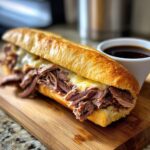 A delicious French Dip sandwich made with leftover prime rib and melted cheese on a crusty roll, served with au jus.