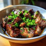 Close-up of juicy Garlic Butter Steak Bites generously sprinkled with fresh parsley in a white bowl.