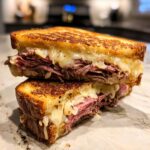 Close-up of a delicious Leftover Prime Rib Sandwich, grilled to golden brown with melted cheese oozing out.