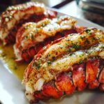 Close-up of three succulent lobster tails, baked and brushed with butter and herbs, ready to be served.