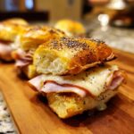 Close-up of a delicious Midnight Snack Slider with melted cheese and ham on a poppy seed bun.