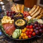 A festive NYE Party Appetizer Board for a crowd, featuring cheese, salami, hummus, olives, grapes, and crackers.