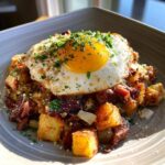 A hearty serving of Prime Rib Hash (Breakfast) topped with a perfectly fried egg and fresh parsley.