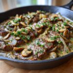 A cast iron skillet filled with Prime Rib Stroganoff, featuring tender beef, sautéed mushrooms, onions, and a creamy sauce, garnished with parsley.