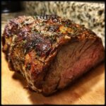A beautifully roasted Ultimate Easy Prime Rib on a wooden cutting board, with a perfectly browned crust and juicy pink interior.