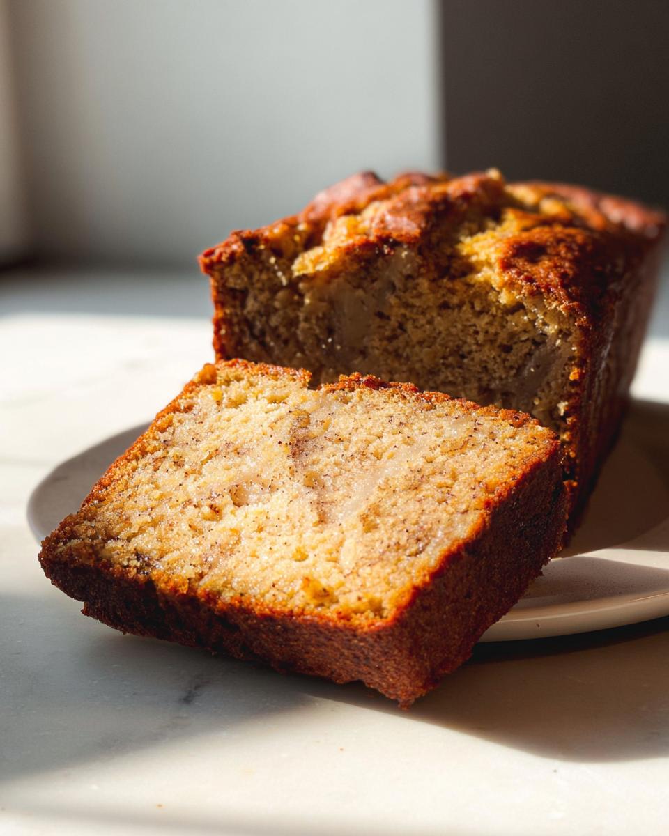 A thick slice cut from a loaf of moist Brown Butter Banana Bread, showing a rich, golden crumb.