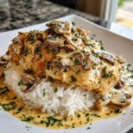 A serving of Creamy Smothered Chicken and Rice topped generously with mushroom gravy and fresh parsley.
