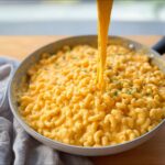 Close-up of creamy macaroni in a skillet with cheese stretching upwards, perfect for an Easy Weeknight Pasta Skillet.