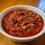 Close-up of a hearty bowl of Healthy Turkey Chili, showing rich red sauce, ground turkey, and dark kidney beans.