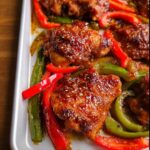 Close-up of glazed Honey Garlic Chicken Thighs (Sheet Pan) with red and green bell peppers.