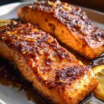 Two glistening fillets of Honey Garlic Salmon covered in a thick, dark glaze with visible minced garlic pieces.
