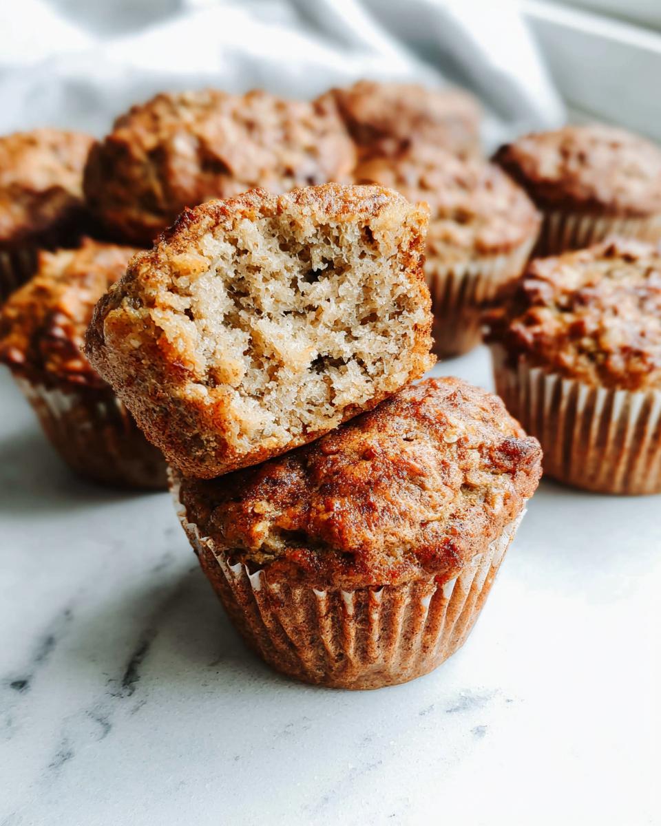 Close-up of a Meal-Prep Banana Bread Muffin broken in half showing a moist, tender crumb.