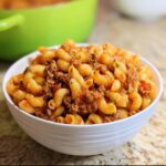 Close-up of a white bowl filled with saucy One-Pot Beef and Macaroni, featuring elbow macaroni and ground beef.