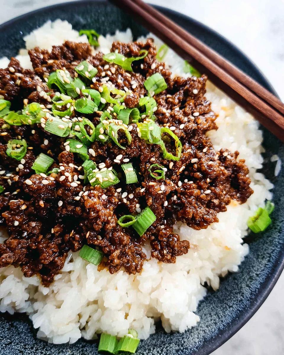 Close-up of a bowl of Korean Ground Beef Bowls (Quick) served over white rice, topped with green onions and sesame seeds.