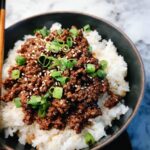 Close-up of Korean Ground Beef Bowls (Quick) served over white rice, topped with green onions and sesame seeds.