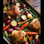 Overhead view of perfectly roasted Sheet-Pan Chicken & Veggies with crispy skin and colorful root vegetables.