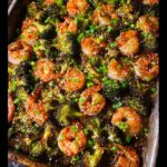 Close-up of roasted Sheet-Pan Shrimp & Broccoli topped with sesame seeds and green onions.