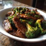 Close-up of a bowl filled with Simple Beef & Broccoli Stir Fry, coated in savory brown sauce.