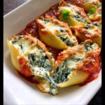 A close-up of baked Spinach & Ricotta Stuffed Shells covered in melted cheese and marinara sauce.