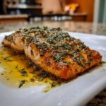 A perfectly cooked salmon fillet with a herb crust, served on a white plate, part of easy healthy dinner recipes.