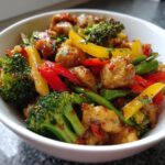 A vibrant bowl of a balanced meal featuring chicken, broccoli, bell peppers, and green beans in a glossy sauce.