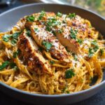 A close-up of delicious Cowboy Butter Chicken Linguine, topped with sliced chicken breast, grated parmesan, and fresh parsley.