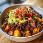 A delicious bowl of crave-worthy ground beef recipe with crispy potato chunks, black beans, guacamole, and pico de gallo.