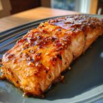 A close-up of a perfectly cooked Crispy Honey Garlic Glazed Salmon fillet with a glossy glaze and visible sesame seeds.