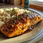 A close-up of a crispy honey garlic glazed salmon fillet served with rice and garnished with parsley.