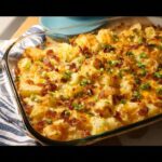 A bubbling casserole dish filled with Easy Mississippi Mud Potatoes, topped with melted cheese, crispy bacon, and green onions.