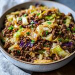 A close-up of a hearty ground beef and cabbage skillet dinner in a bowl, garnished with parsley.