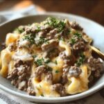 A close-up of a bowl of creamy Ground Beef Stroganoff with pasta, topped with fresh parsley.