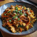 A close-up of a healthy chicken and quinoa stir-fry with carrots, onions, and green onions, part of healthy meals you can prep in under 1 hour.