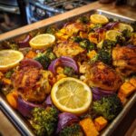 A vibrant and healthy one-pan recipe featuring roasted chicken thighs, sweet potatoes, broccoli, red onion, and lemon slices.