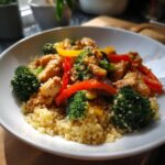A vibrant bowl of high-protein healthy dinner featuring chicken, broccoli, bell peppers, and quinoa.