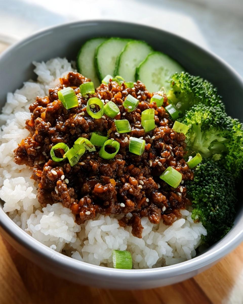 A close-up of a Korean Ground Beef Bowl with rice, seasoned ground beef, broccoli, and sliced cucumbers.