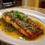 A perfectly cooked salmon fillet with garlic lemon butter sauce and fresh parsley, a delicious salmon recipe.