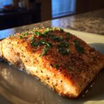 A perfectly cooked piece of Simple Texas Roadhouse Salmon, seasoned and garnished with parsley.